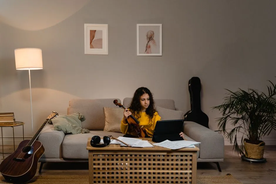 Adolescentă cântând la vioară în sufragerie, cu partitura alături