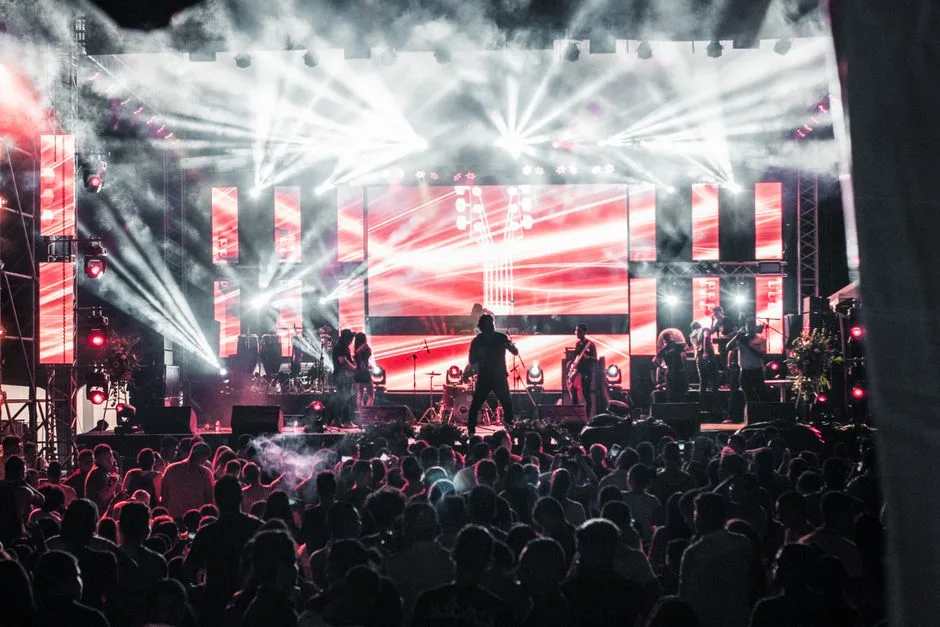 Concert live cu artiști pe o scenă puternic iluminată