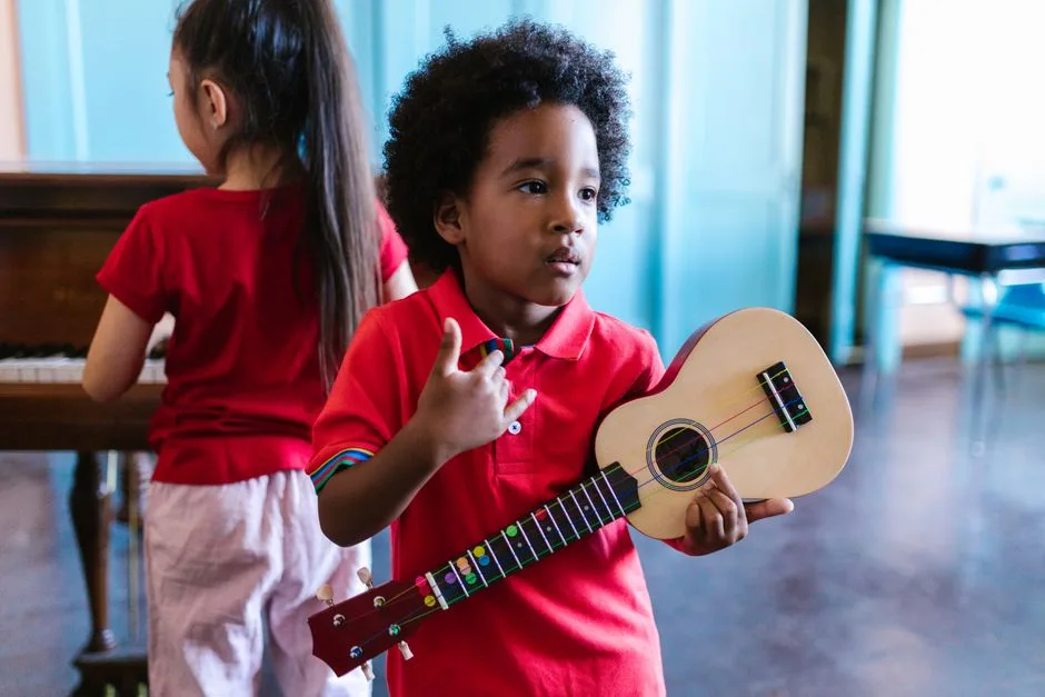 Doi copii cântând, unul la ukulele și celălalt la pian, într-o cameră luminoasă