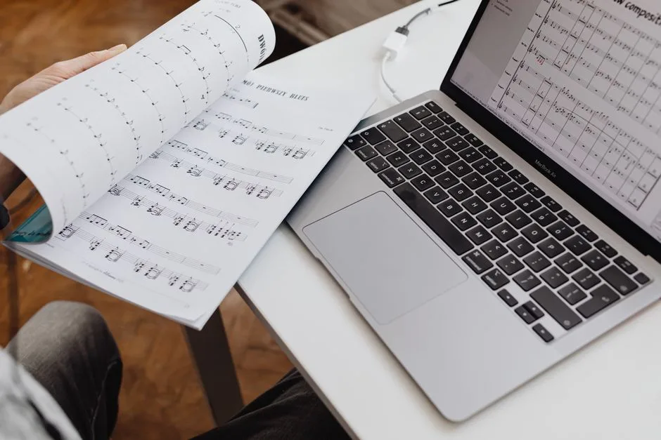 Partitură așezată lângă un laptop, pe un birou