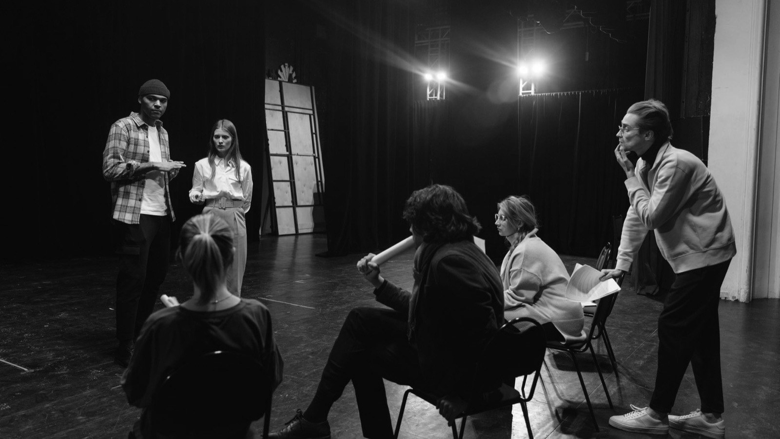Grup de cursanți la repetiție de actorie pe scenă, alături de trainer
