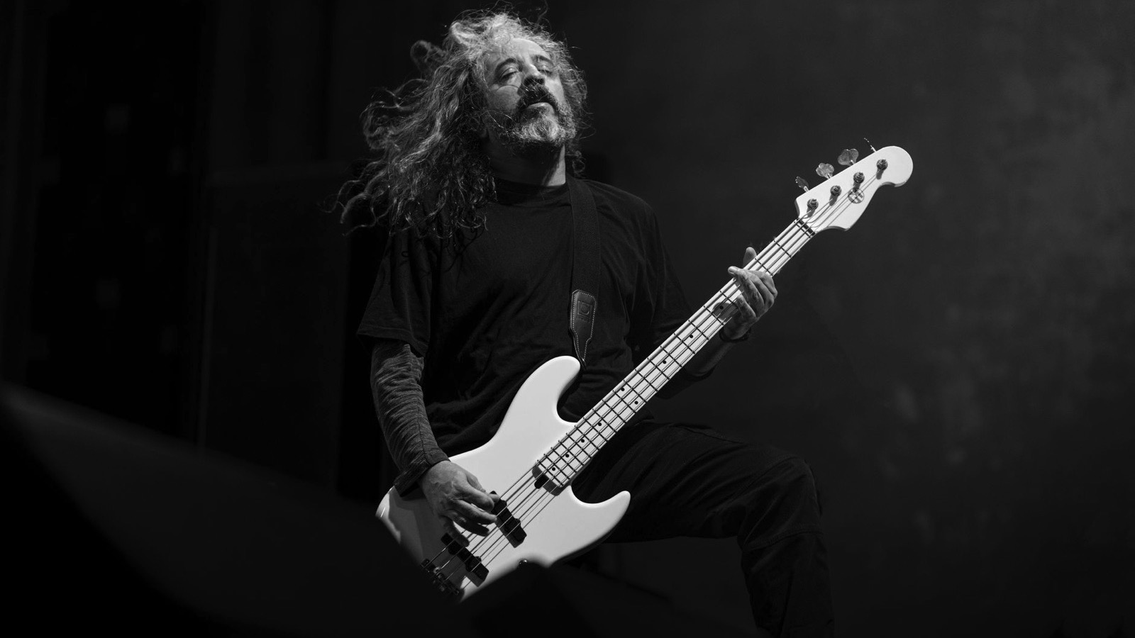 Basist cântând la chitară bass pe scenă, în lumini de concert