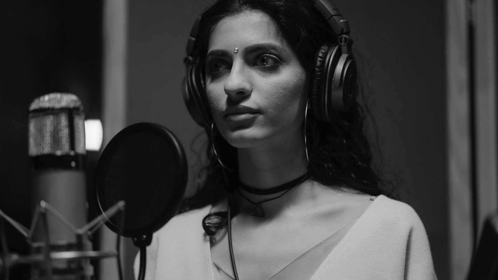 Cursantă la curs de canto, cântând la microfon de studio cu căști, la VOLTAJ Academy
