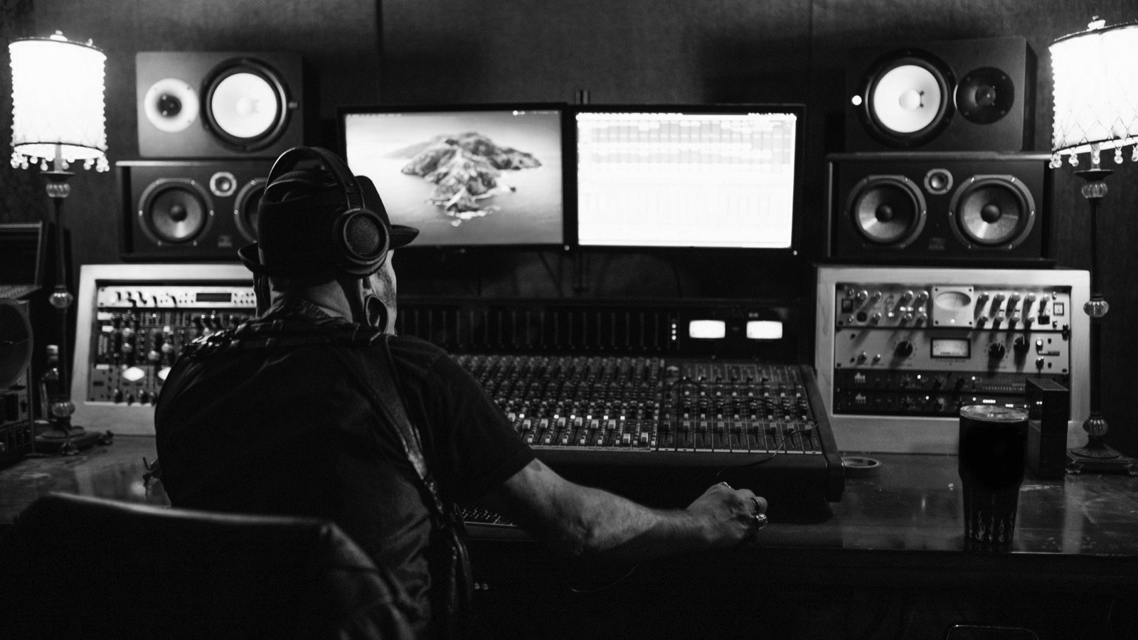 Producător muzical la consola de mixaj, în fața monitoarelor de studio